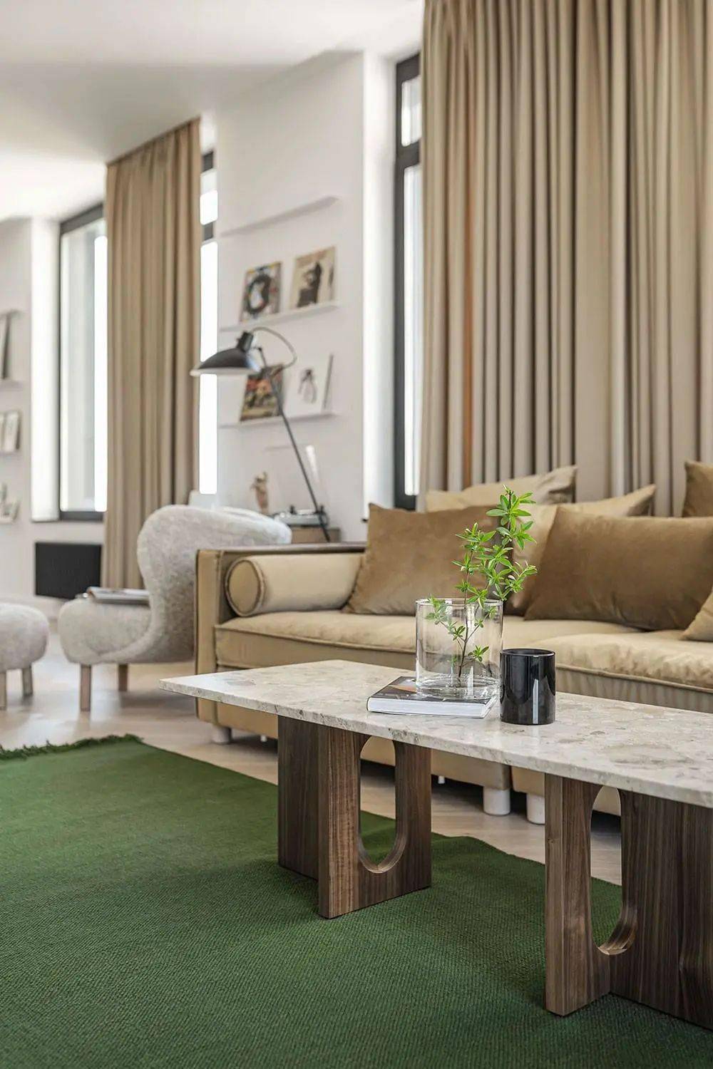 棕色皮质沙发倚窗而立,地面全部用木质地板装饰,卡其色窗帘与沙发