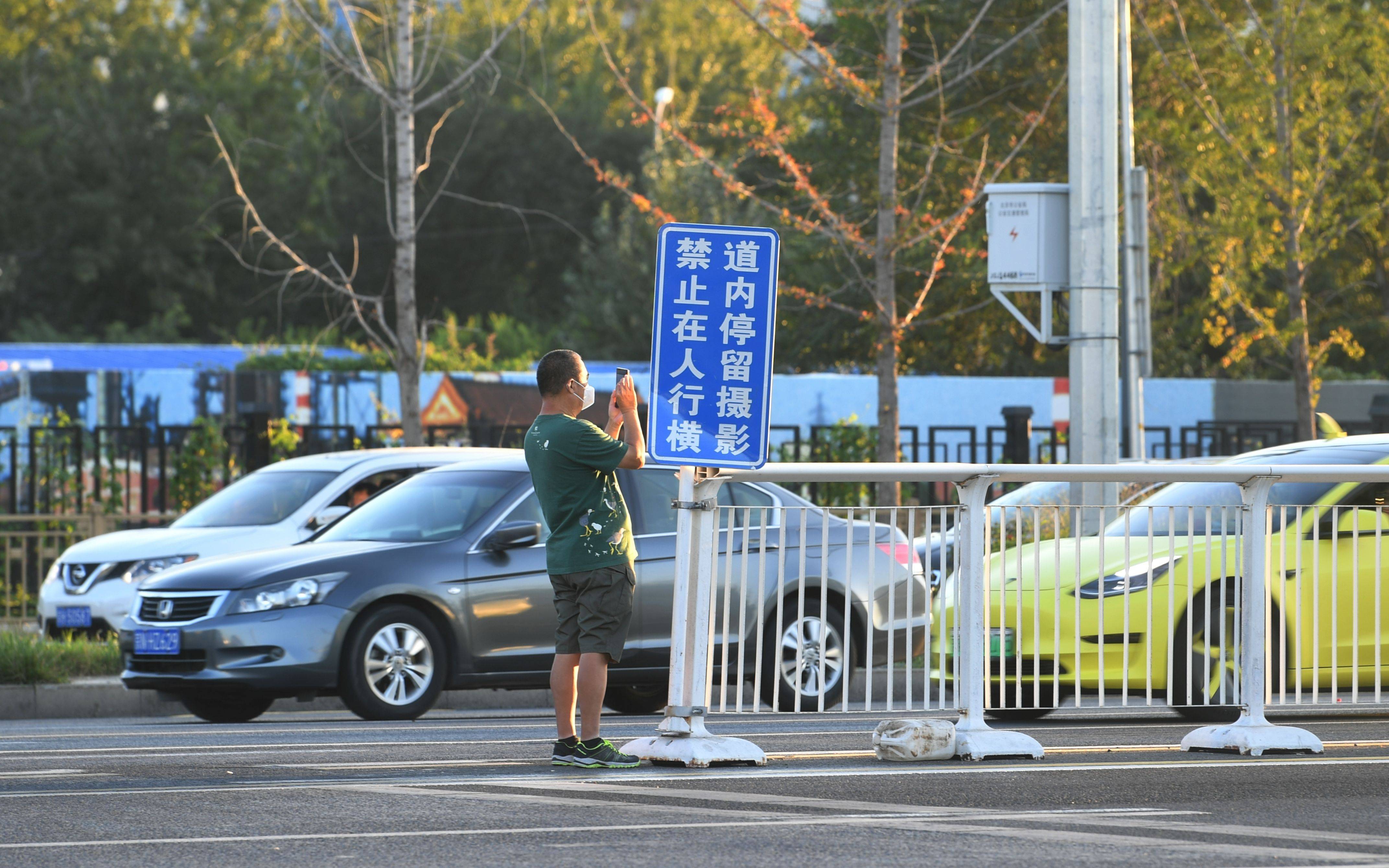 一位市民在警示牌旁拍照.