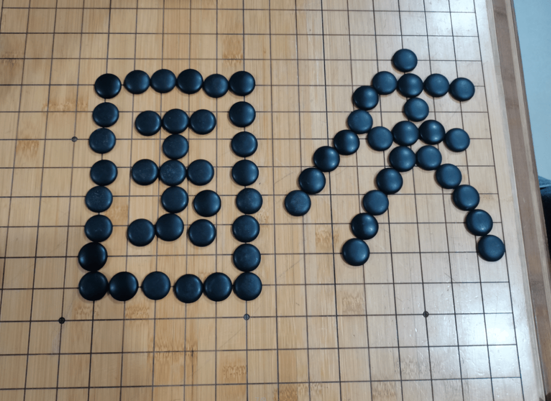棋子在棋盘上摆出了"国庆"字样,同时还跟着老师学习了围棋小技巧和