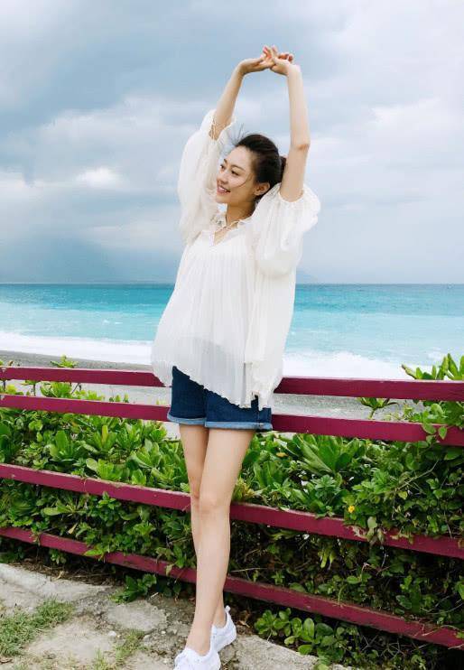 黄梦莹身穿一件蓝白条纹衬衫,搭配白色短裙,手拎蓝色帆布包,悠闲自得