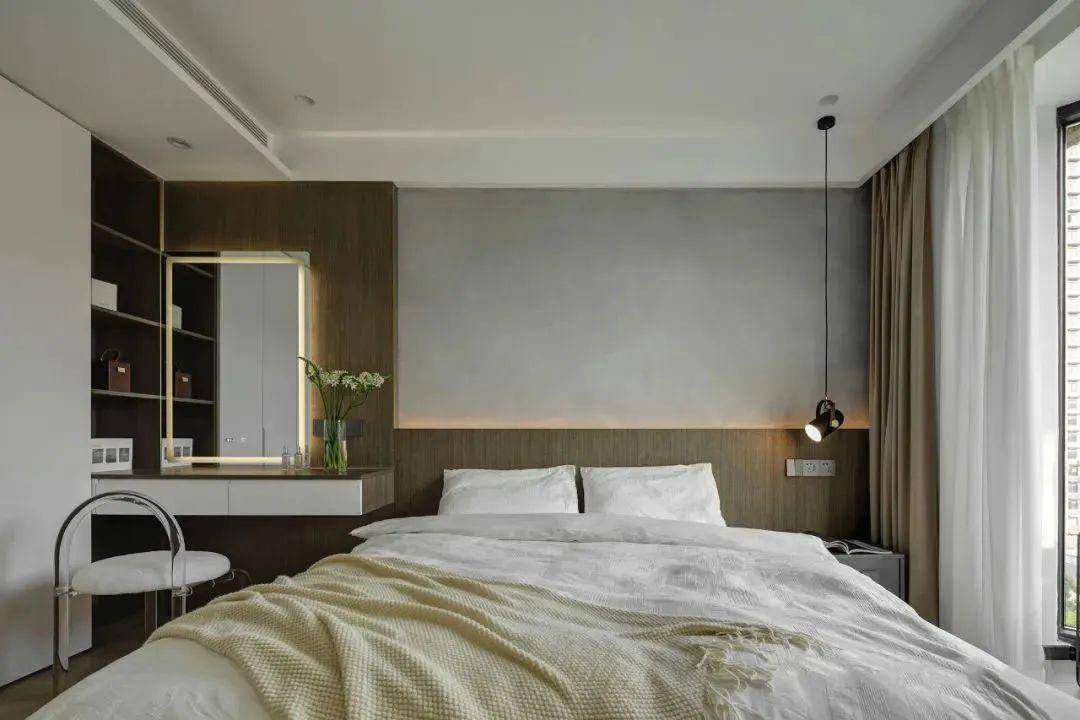 床头背景墙,采用l型木饰面拼接微水泥质感墙,一侧衣柜延伸打造梳妆
