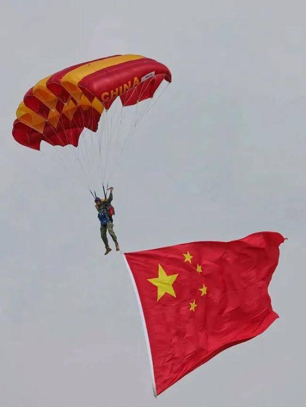 八一跳伞队队员携党旗,国旗,八一军旗和空军军旗从飞机上一跃而下