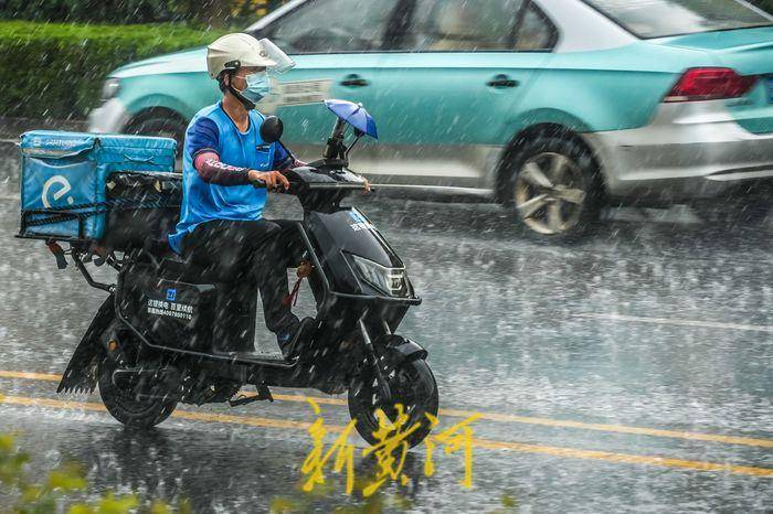 市区中午突降大雨 市民雨中小心前行