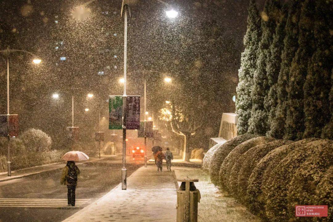 若隐若现朦胧在暖光里划过橘色的路灯纷飞的雪花夜色为雪景施了魔法