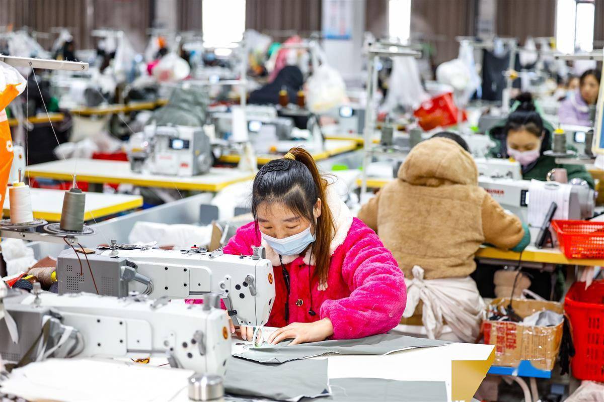 2023年12月15日,在汉川闽商钰沣服饰项目羽绒服生产车间内,工人们正在