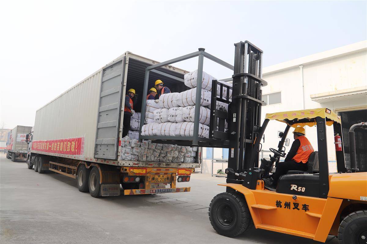 几辆超长卡车一字排开,一辆辆叉车从仓库转运物资出库,工人们正在整理
